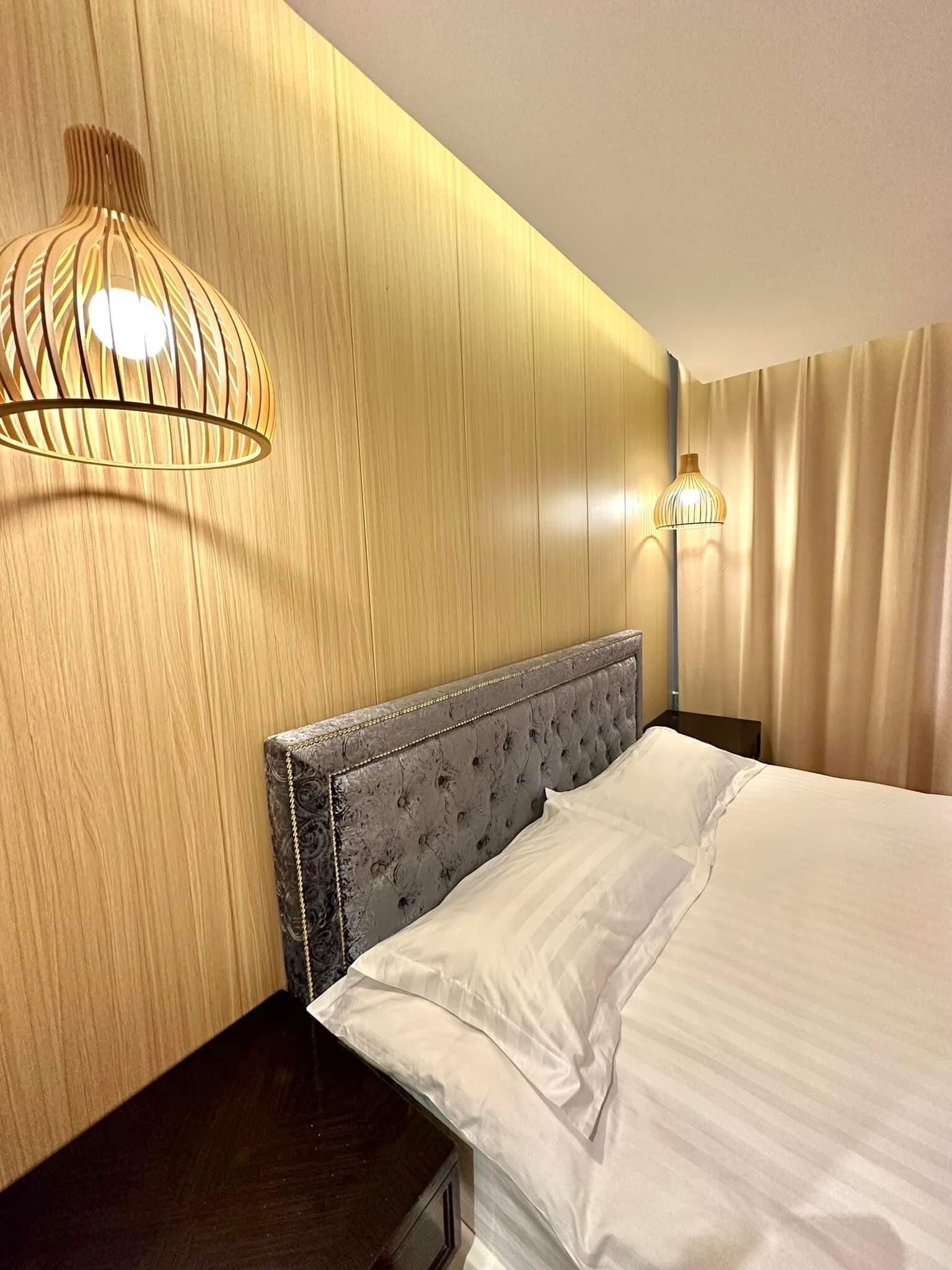 A hotel room with a wooden headboard, a bed with white linens, and two wall-mounted lamps.