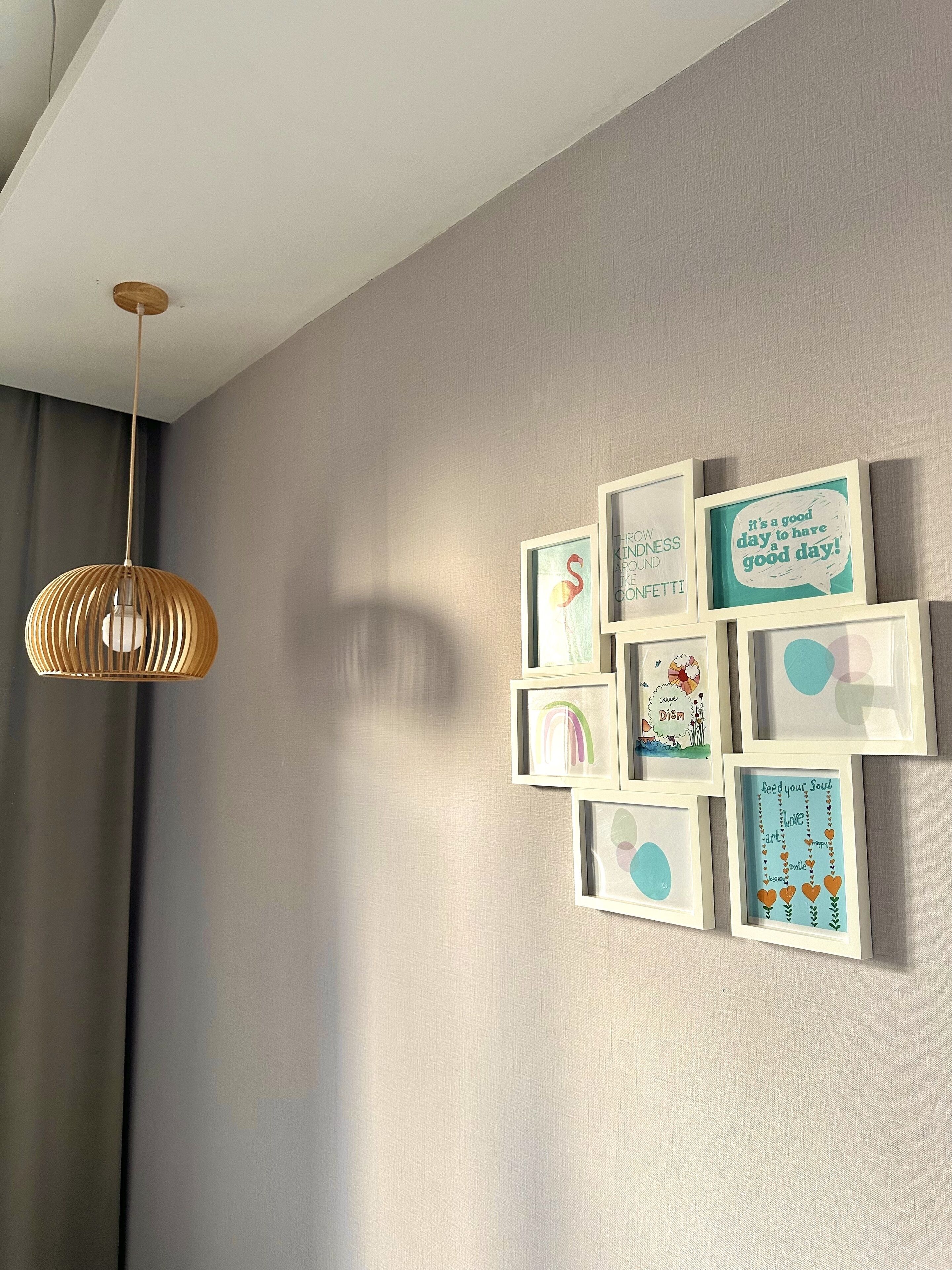 A wall with framed artwork and a hanging light fixture.