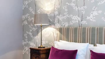 Um quarto com uma cama, almofadas, uma luminária e uma mesa de cabeceira.