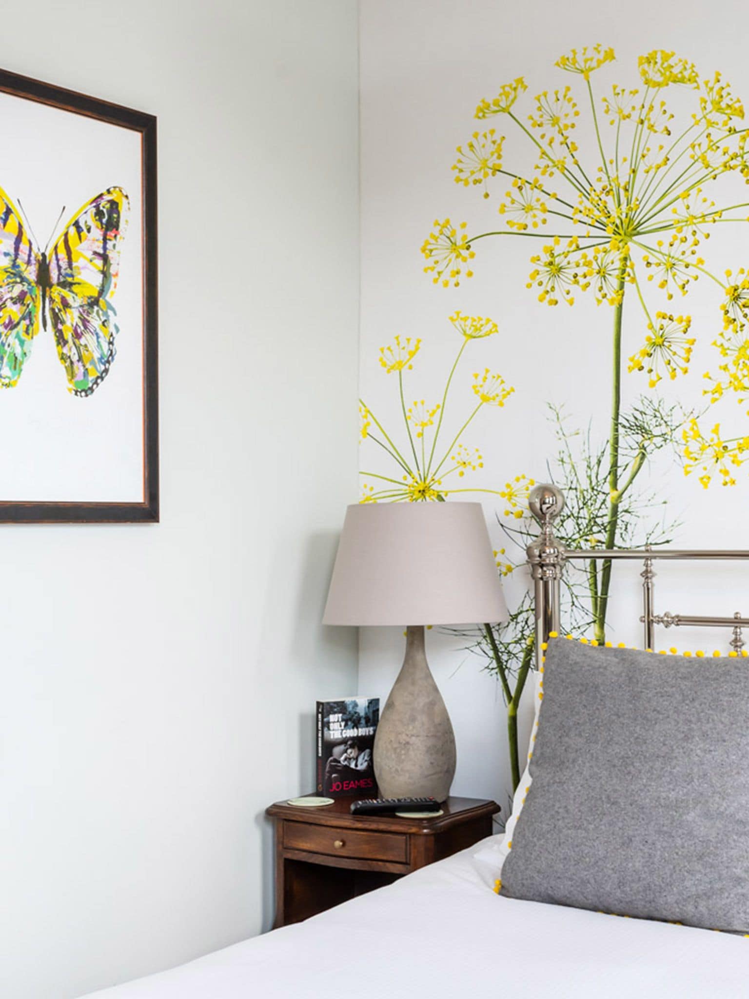 A bedroom with a bed, a nightstand with a lamp, a framed picture, and a wall decoration.
