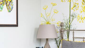 A bedroom with a bed, a nightstand with a lamp, a framed picture, and a wall decoration.