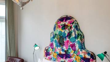 A bedroom with a bed, a chandelier, a chair, and a lamp.