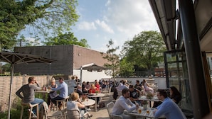 An outdoor seating area with tables and chairs, surrounded by a brick wall and trees. - The High Field Town House (Birmingham)