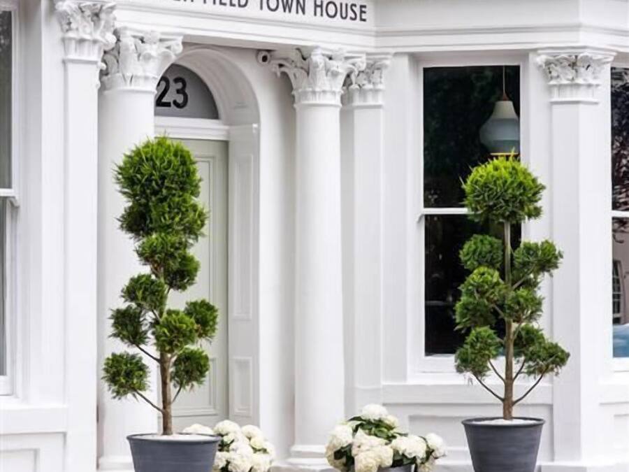 The exterior of The High Field Town House, featuring a classical architectural style with white columns and a prominent entrance number 23.