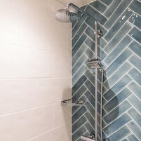 Una ducha con cabezal de lluvia y cabezal de ducha manual, grifo de cromo y panel de control de ducha cromado.