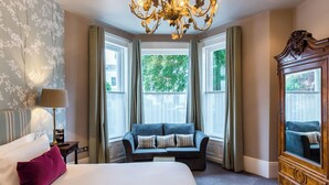 A hotel room with a large bed, a sofa, a chandelier, and a large mirror. - The High Field Town House (Birmingham)