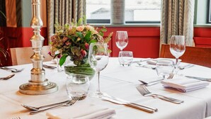 A dining table set for two with a candle, a vase of flowers, and a window view. - The High Field Town House (Birmingham)