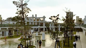 An outdoor area with a water feature, seating, and a modern building in the background.