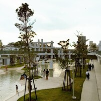 An outdoor area with a water feature, seating, and a modern building in the background.