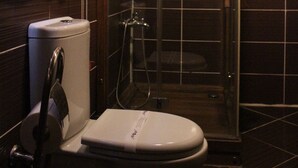 A bathroom with a toilet, a glass-enclosed shower, and a towel rack. - Mihran Hanım Konagi (Edirne)