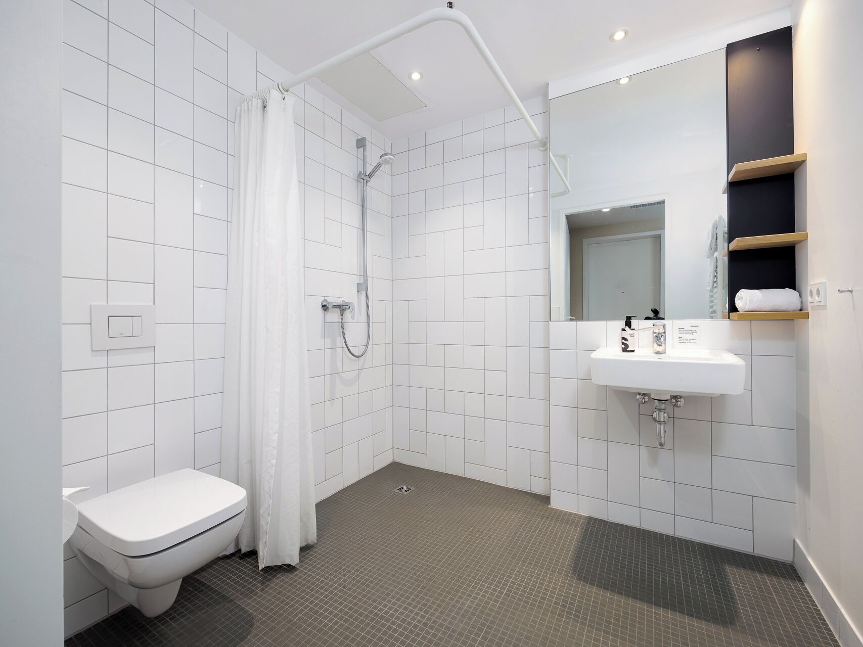 A modern bathroom with a shower, toilet, and sink.