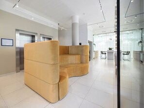 A modern lobby with a large, curved seating area, a reception desk, and a visible elevator. - smartments Berlin Prenzlauer Berg (Berlin)