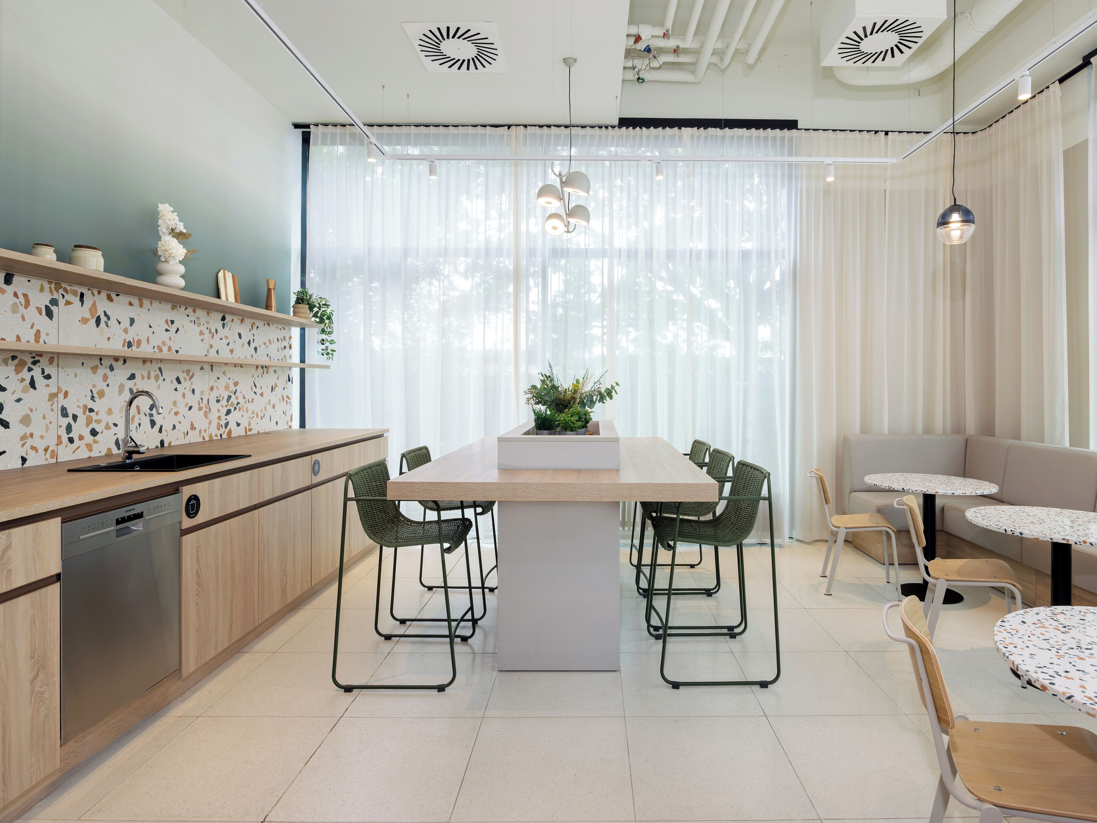 Una cocina moderna con una isla central, taburetes de bar y una mesa de comedor.