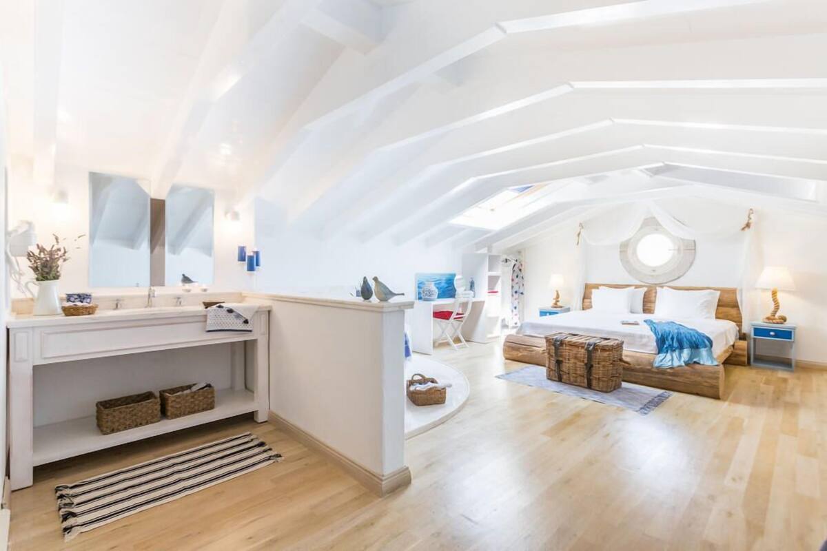 A modern bedroom with a skylight, a wooden bed, a bedside table, and a large mirror.