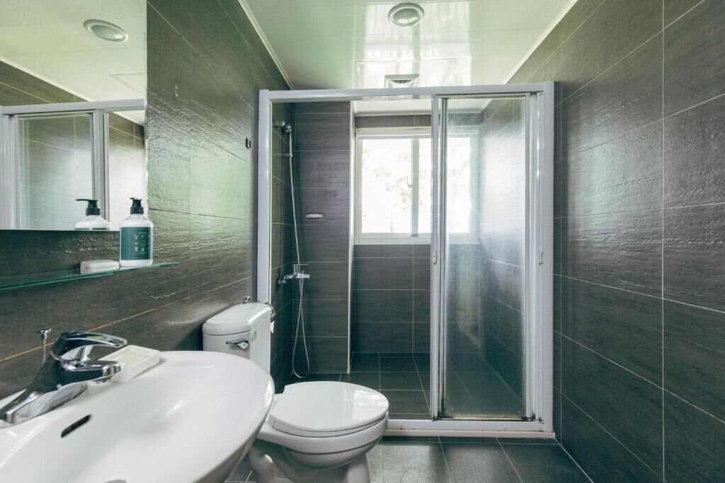 Un bagno moderno con doccia vetrata, un lavandino bianco e un water.