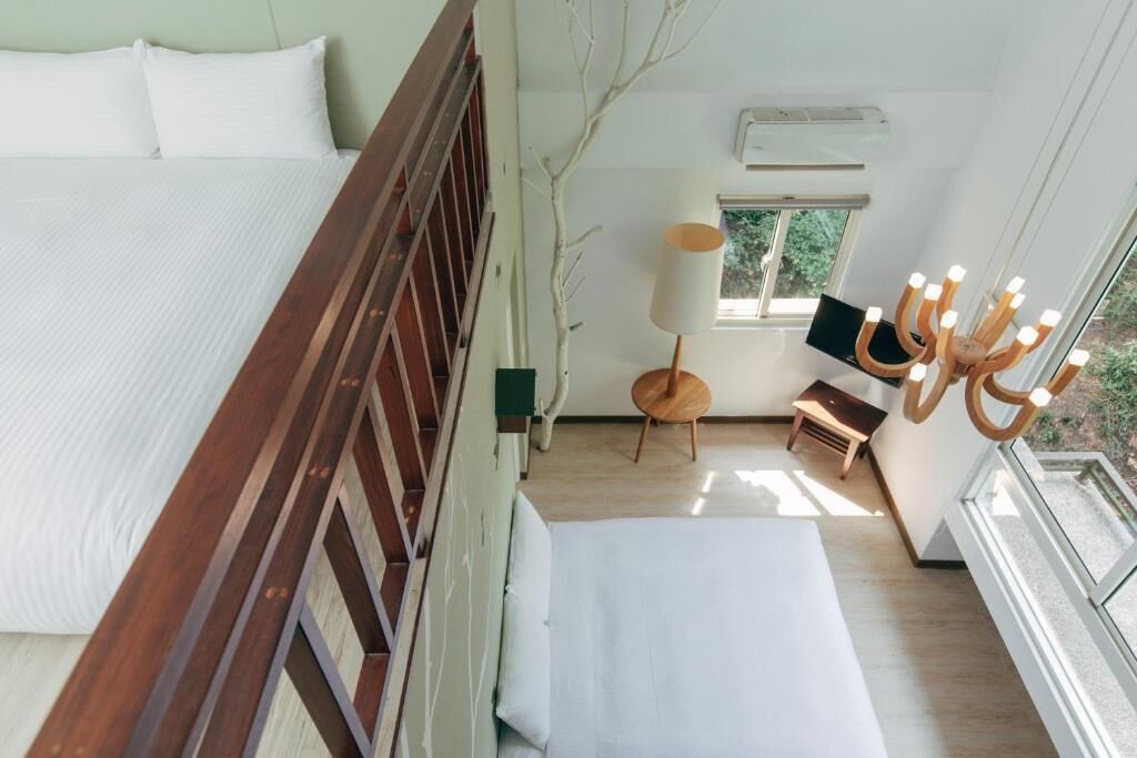 A bedroom with a wooden bed, a small table, a chair, a lamp, and a candelabra.