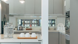 A modern kitchen with stainless steel appliances, a coffee station, and a view of the outdoors through the window. - Lvbolang by REINDEER, Sanyi (Sanyi)