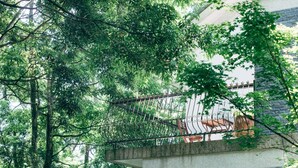 A balcony with a wrought iron railing overlooking a lush green area. - Lvbolang by REINDEER, Sanyi (Sanyi)