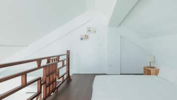 A bedroom with a wooden bed, a nightstand, a lamp, and a white wall with two small pictures.