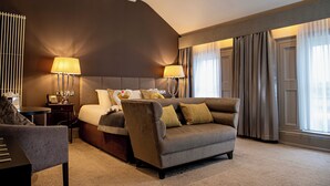 Une chambre d’hôtel avec un lit, un canapé, une table de chevet et une lampe.