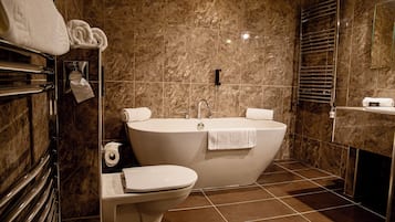 A modern bathroom with a freestanding bathtub, a toilet, and a towel rack with towels.