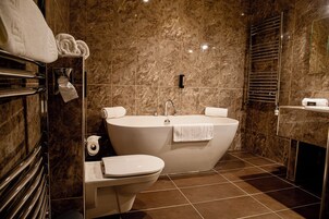 A modern bathroom with a freestanding bathtub, a toilet, and a towel rack with towels.