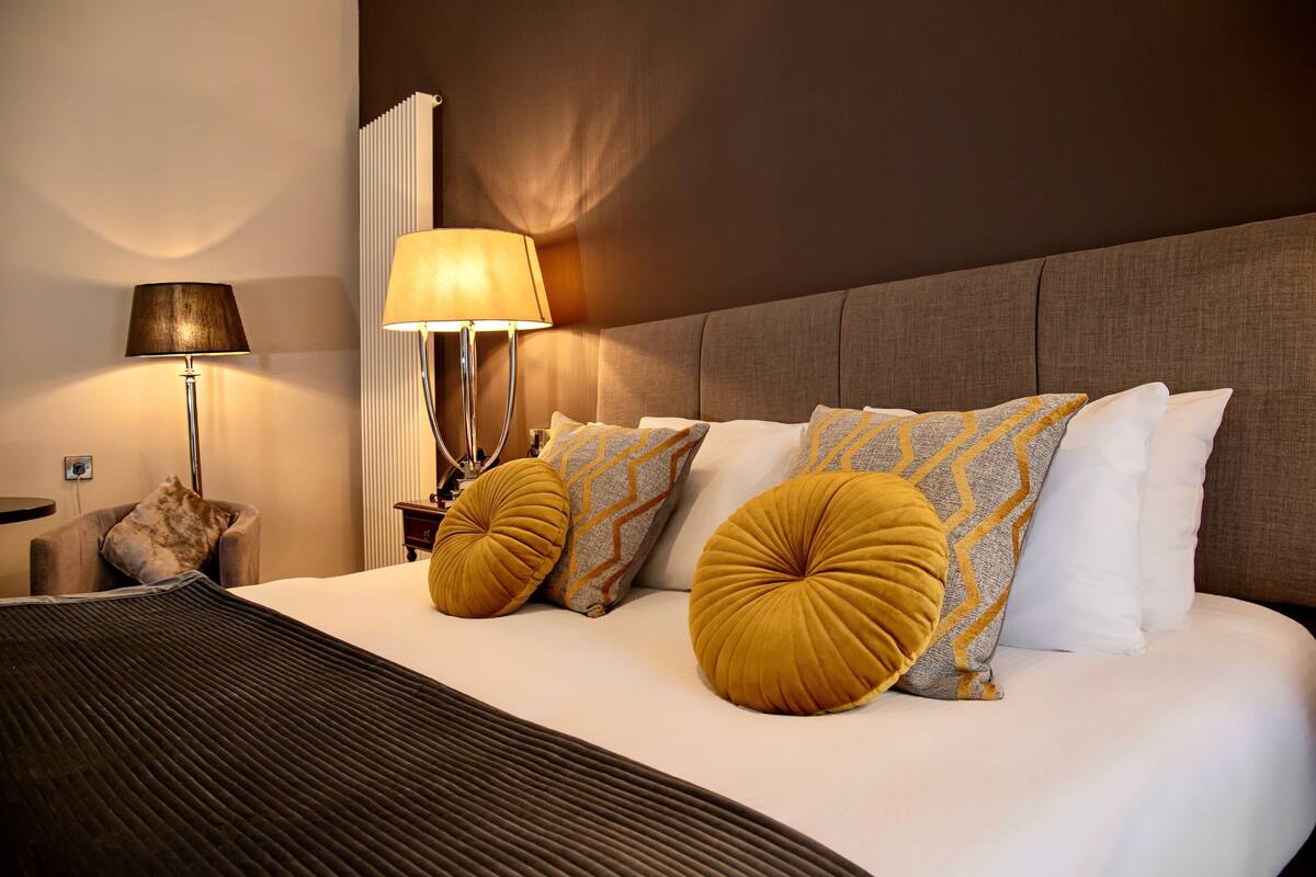 Habitación de hotel con una cama grande, dos lámparas de noche y vistas al horizonte de la ciudad.