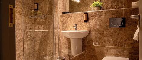 A modern bathroom with a glass shower enclosure, a pedestal sink, and a toilet.