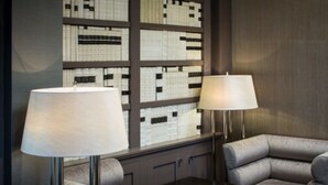 Une chambre d’hôtel moderne avec un canapé d’angle, une petite table et deux lampadaires.