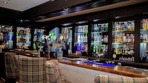 Un espace bar doté de plusieurs étagères remplies de bouteilles d’alcool, de tabourets de bar et d’un comptoir.