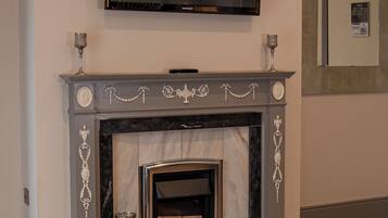 A fireplace with a TV mounted above it, a sofa in front, and a door to the right.