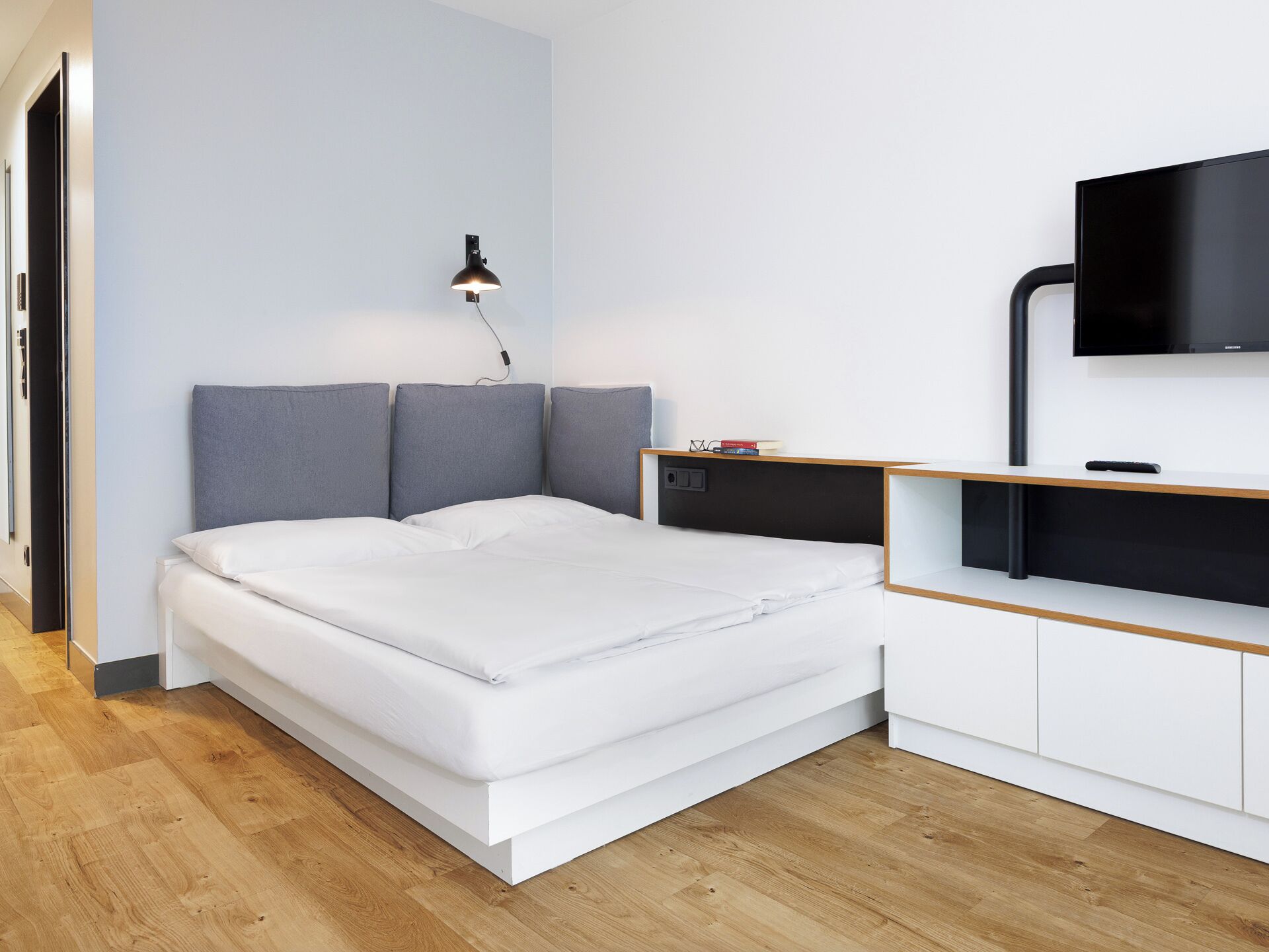 A modern bedroom with a bed, a bedside table, a lamp, and a TV.