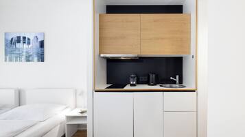 A compact kitchenette with a stove, coffee maker, and sink.