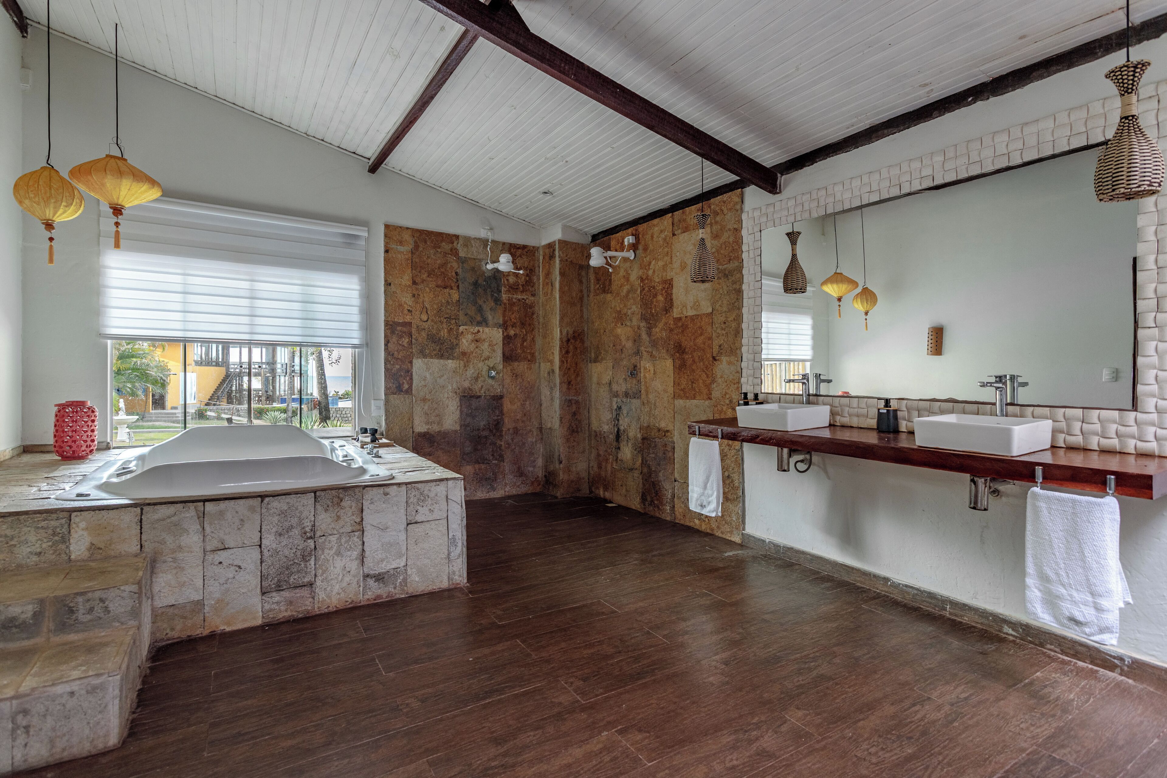 A modern bathroom with a stone bathtub, dual sinks, and a large mirror.