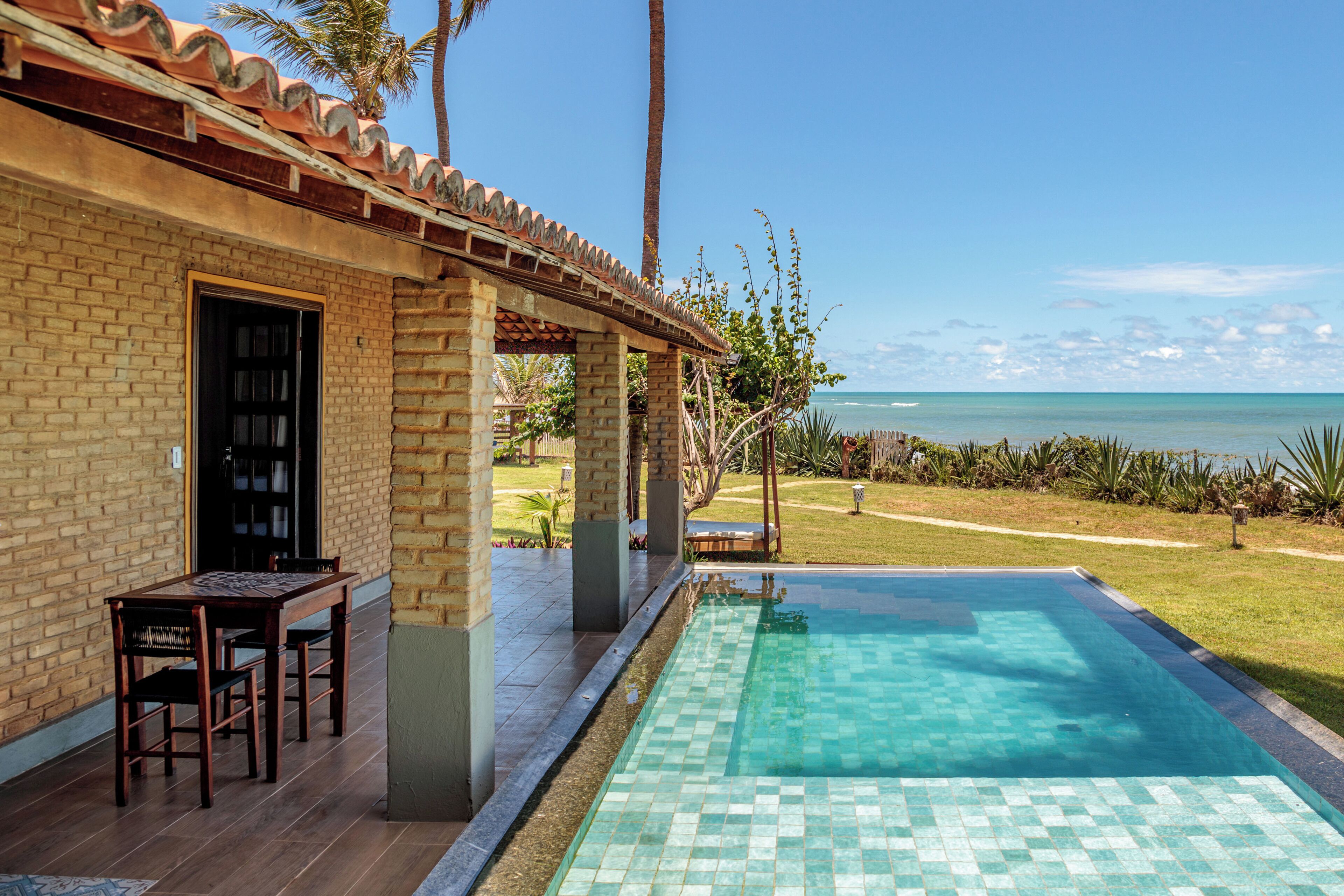 A brick building with a pool, a table, and chairs outside.