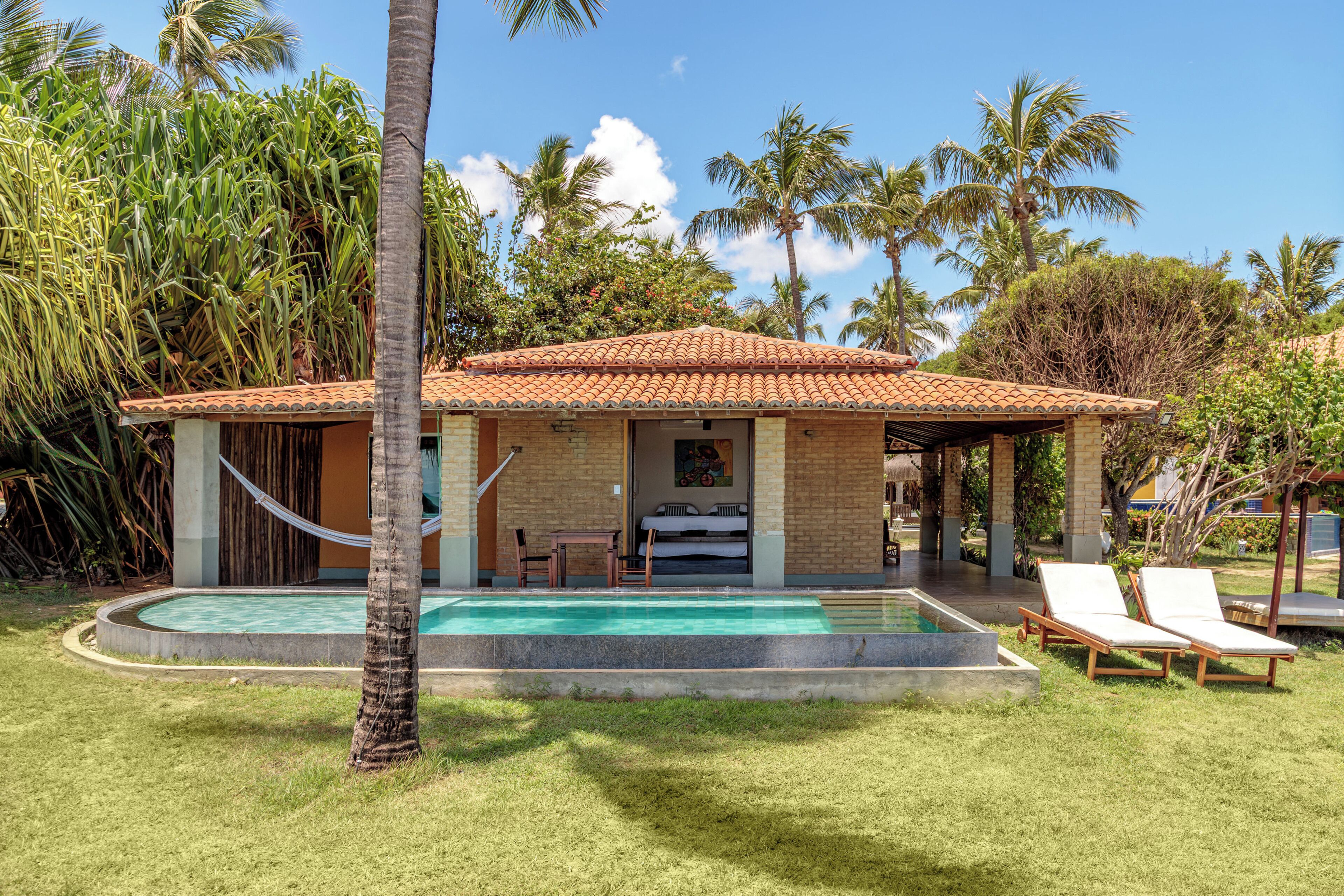 A house with a swimming pool, a covered patio, and lounge chairs.