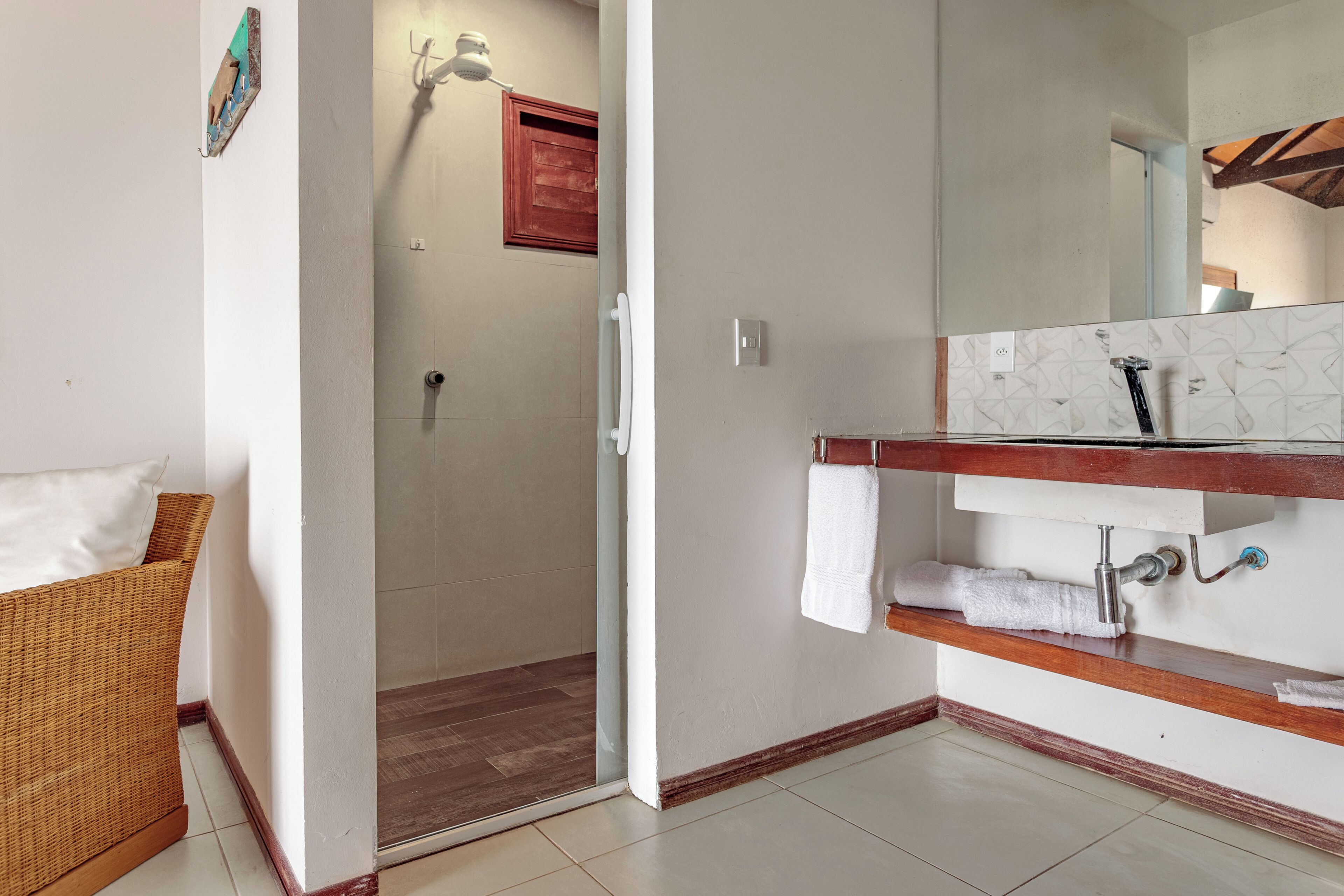 Ein Badezimmer mit Dusche, Spiegel, Handtuchhalter und einem Holzregal.
