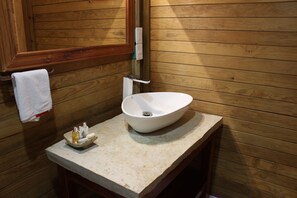 A wooden cabin-style bathroom with a white vessel sink, a wooden vanity, and a towel hanging on the wall. - Winíka Alterra (Palenque)