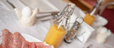 Una mesa de desayuno con diversos alimentos, incluyendo carnes, queso y una botella de jugo de naranja.