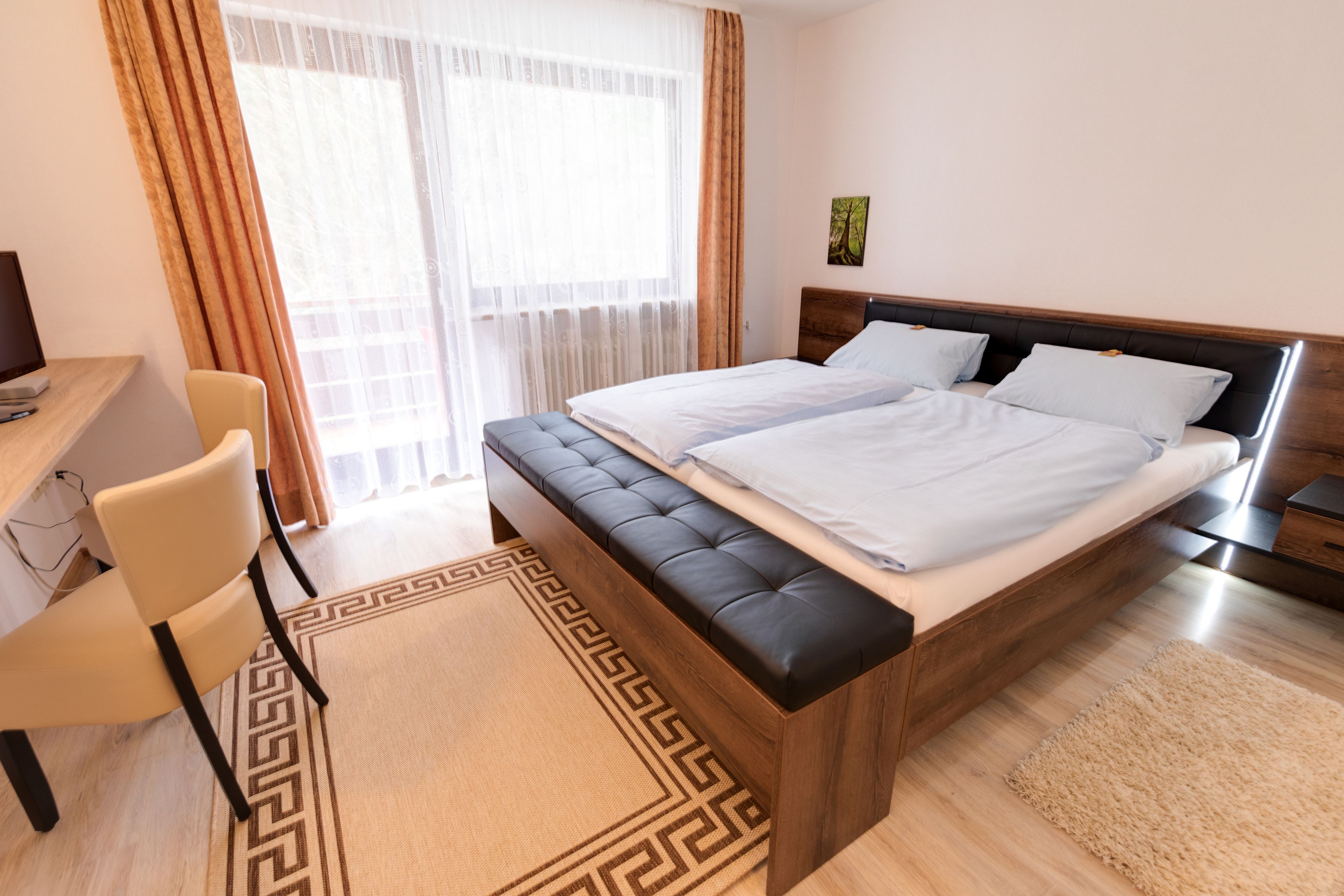 Ein Hotelzimmer mit Bett, Schreibtisch, Stuhl und Blick ins Freie.