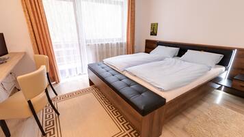 Ein Hotelzimmer mit Bett, Schreibtisch, Stuhl und Blick ins Freie.