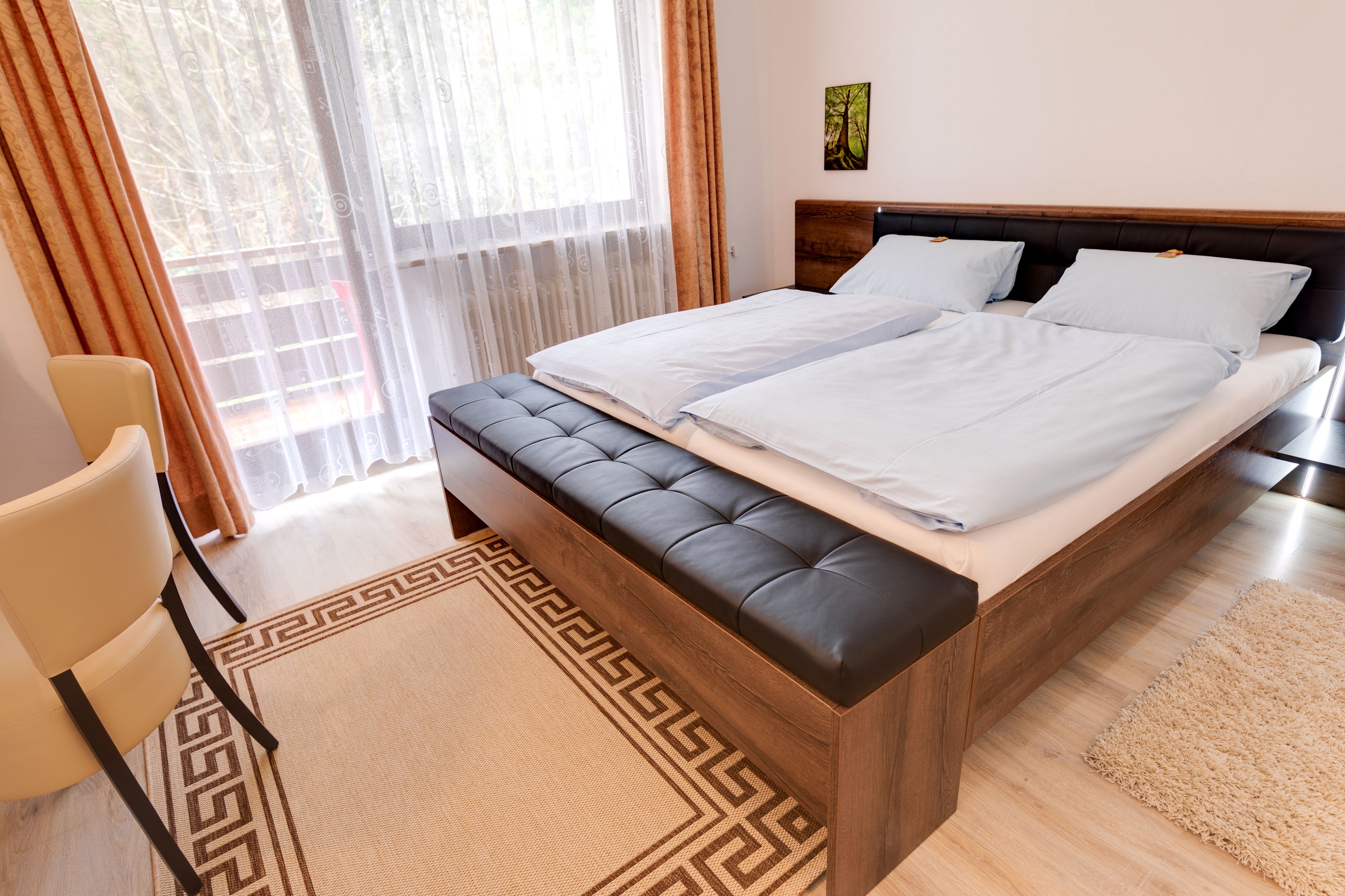 Un dormitorio moderno con una cama grande, un cabecero de madera y un banco al pie de la cama.