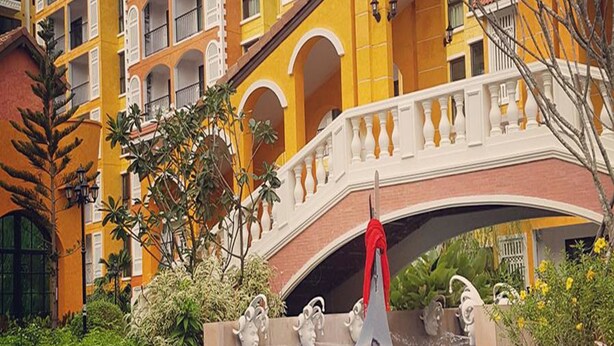 A hotel with a swimming pool featuring a decorative bridge and statues. - The Symphony Suites Pattaya (Pattaya)