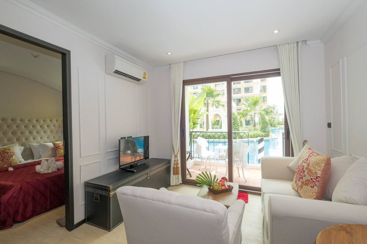 A modern living room with a television, sofa, and a dining area with a table and chairs.