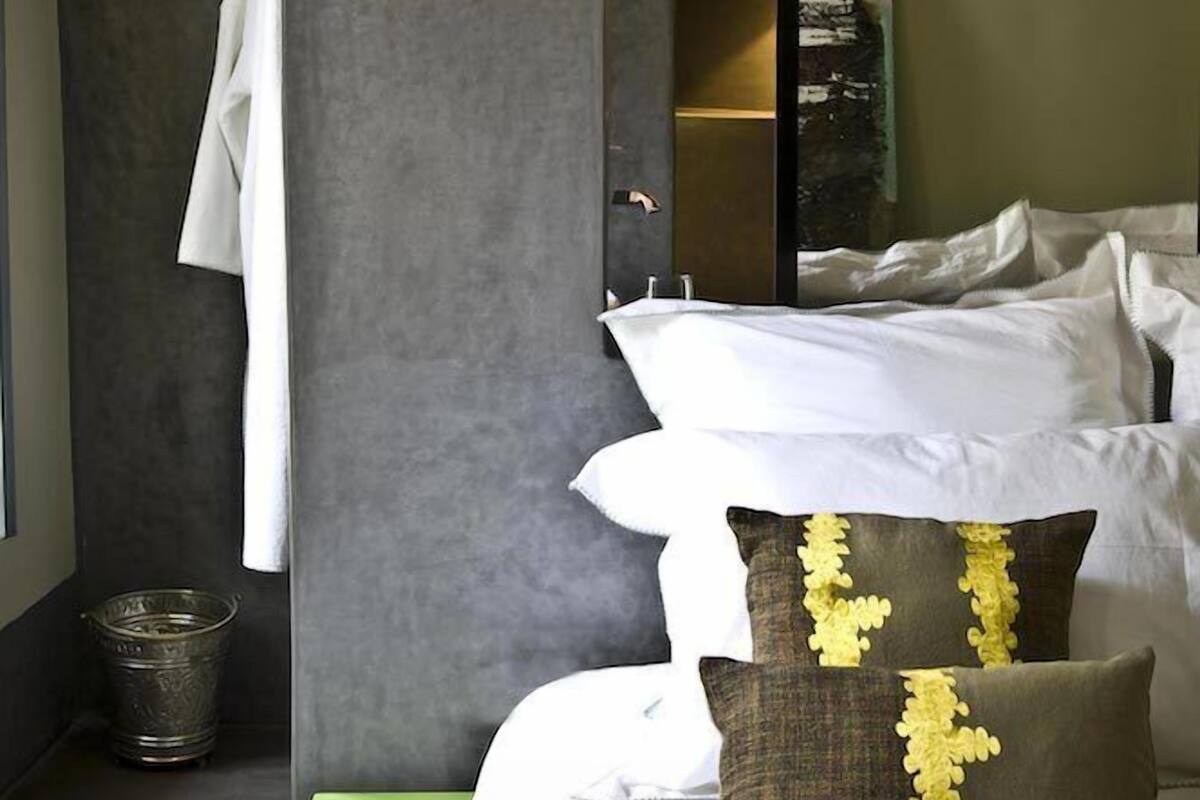 A modern bedroom with a large bed, a green nightstand, and a mirror above the bed.