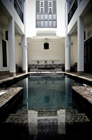 Een buitenzwembad, ligstoelen bij het zwembad