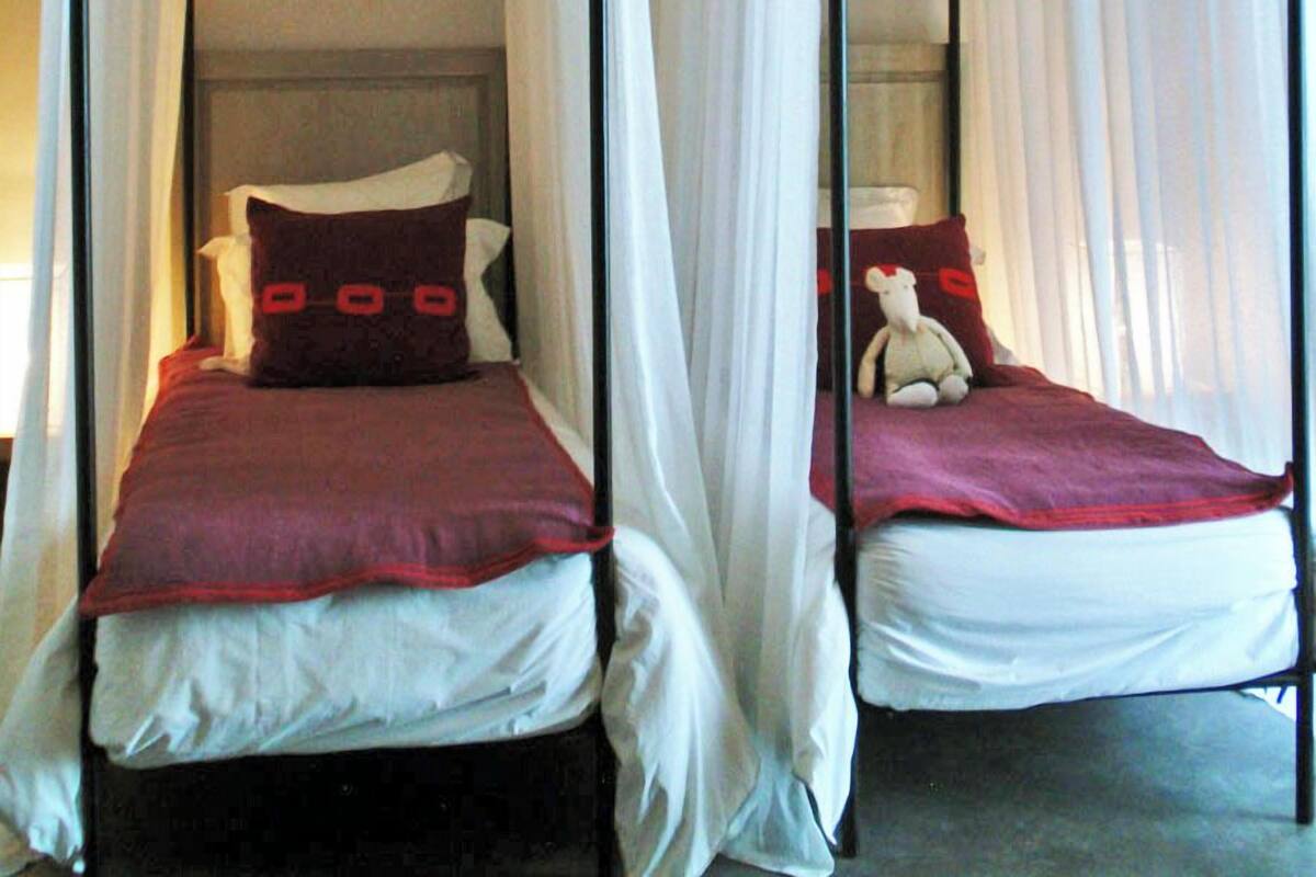 Two single beds with canopy beds in a room.