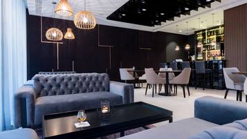 Ein stilvoller Lounge-Bereich mit gepolstertem Sofa, einem Couchtisch mit Kerze und einer Bar mit Flaschenregalen.