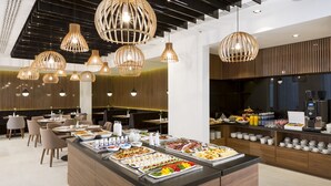 Restaurante moderno com buffet, painéis de madeira e iluminação pendente.