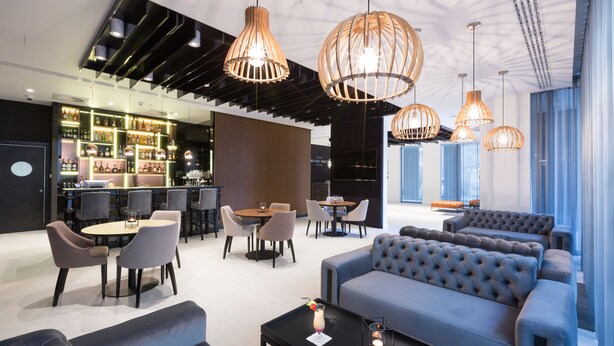 Um saguão de hotel moderno com área de bar, assentos e luminárias com design exclusivo.